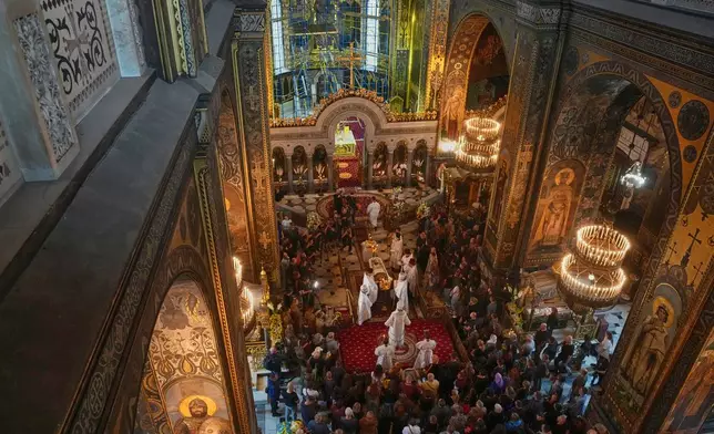 Priests preside over a farewell ceremony for Oleksiy Yukov, who was fatally wounded while exhuming bodies of killed soldiers in the frontline in Donetsk region, in St. Volodymyr Cathedral in Kyiv, Ukraine, Saturday, Aug. 8, 2026. (AP Photo/Efrem Lukatsky)