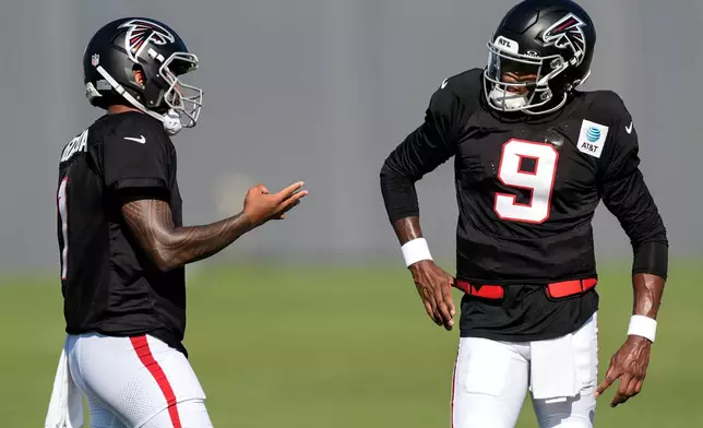 Atlanta Falcons quarterback Michael Penix Jr. (9) and Tua Tagovailoa speak during a Atlanta Falcons training camp, Monday, Aug. 3, 2026, in Flowery Branch, Ga. (AP Photo/Mike Stewart)