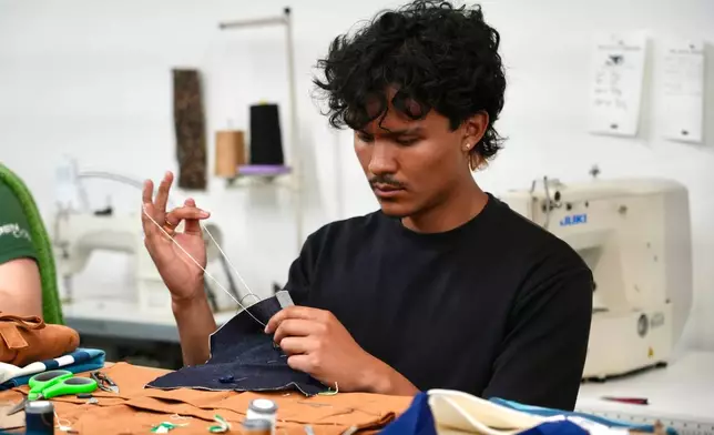 Jesse Sanchez practices sewing during a clothing repair workshop at a Levi's retail store in downtown San Francisco, Wednesday, July 22, 2026. (AP Photo/Terry Chea)