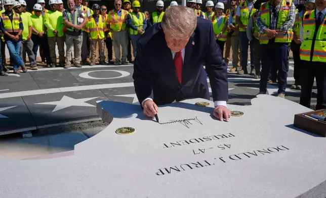 President Donald Trump signs a stone outside the White House, Wednesday, Aug. 19, 2026, in Washington, at the construction site of the new helicopter landing zone on the South Lawn of the White House. (AP Photo/Manuel Balce Ceneta)
