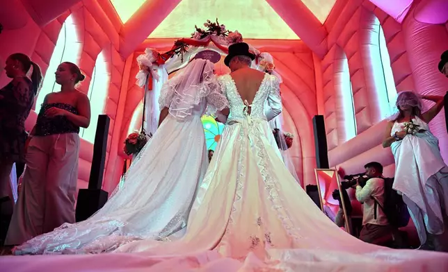 A couple prepare to exchange vows during a mass wedding ceremony in an inflatable chapel in Amsterdam, Netherlands, Thursday, Aug. 6, 2026, as part of Pride events celebrating 25 years since the Netherlands became the first country in the world to legalize same-sex marriage. (AP Photo/Mouneb Taim)