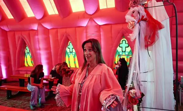 Julia van den Beek officiates during a mass wedding ceremony in an inflatable chapel in Amsterdam, Netherlands, Thursday, Aug. 6, 2026, as part of Pride events celebrating 25 years since the Netherlands became the first country in the world to legalize same-sex marriage. (AP Photo/Mouneb Taim)