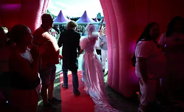 Newlyweds walk out of an inflatable chapel after tying the knot during a mass wedding ceremony in an inflatable chapel in Amsterdam, Netherlands, Thursday, Aug. 6, 2026, as part of Pride events celebrating 25 years since the Netherlands became the first country in the world to legalize same-sex marriage. (AP Photo/Mouneb Taim)