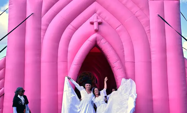 Newlyweds pose for photos after tying the knot during a mass wedding ceremony in an inflatable chapel in Amsterdam, Netherlands, Thursday, Aug. 6, 2026, as part of Pride events celebrating 25 years since the Netherlands became the first country in the world to legalize same-sex marriage. (AP Photo/Mouneb Taim)