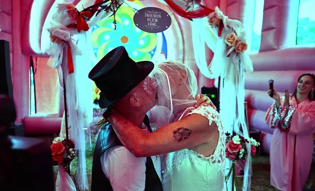Jan Derksen-Wynn, right, and and John Wijfjes kiss after exchanging vows during a mass wedding ceremony in an inflatable chapel in Amsterdam, Netherlands, Thursday, Aug. 6, 2026, as part of Pride events celebrating 25 years since the Netherlands became the first country in the world to legalize same-sex marriage. (AP Photo/Mouneb Taim)