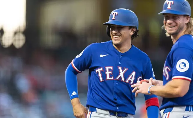 Texas Rangers' Nicky Lopez smiles with Texas Rangers first base coach Travis Jankowski after being hit by a pitch in the second inning of a baseball game against the Los Angeles Angels Wednesday, Aug. 12, 2026, in Anaheim, Calif. (AP Photo/Karl Anderson)