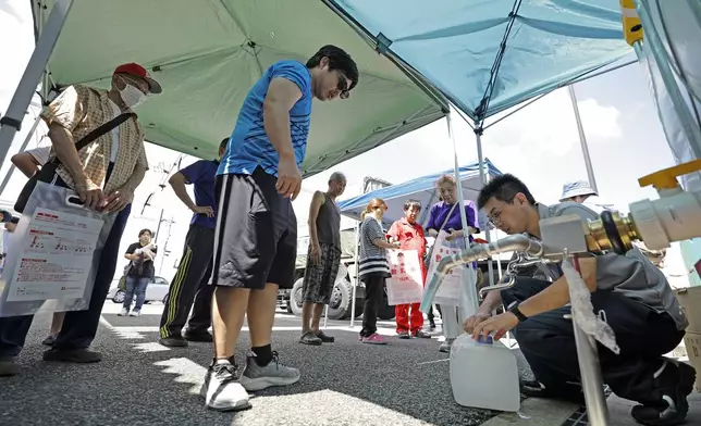 Residents receive water supplies at Hikawa town hall as an earthquake disrupted water service in Hikawa, Kumamoto Prefecture, southern Japan, Friday, July 31, 2026. (Atsuhiro Maeda/Kyodo News via AP)