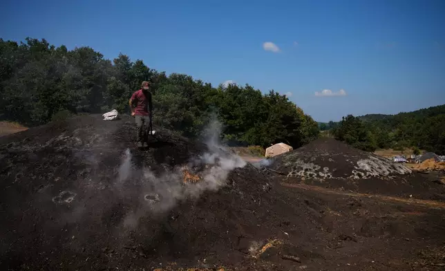Mehmet Durak tends the kilns at a charcoal production site in a forest in Kocaeli province, Turkey, Tuesday, Aug. 25, 2026. A handful of family-run producers continue the region’s traditional practice of slowly carbonizing hardwood in earthen kilns to make charcoal for barbecues and restaurants. (AP Photo/Khalil Hamra)