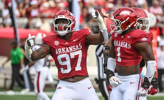 FILE - Arkansas defenders Quincy Rhodes Jr. (97) and Phillip Lee (1) celebrate after a big defensive stop against Arkansas State during an NCAA football game, Sept. 6, 2025, in Little Rock, Ark. (AP Photo/Michael Woods, File)