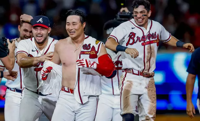 Atlanta Braves pinch-hitter Ha-Seong Kim, center, is mobbed by teammates Victor Mederos, left, and Mauricio Dubón, right, after Kim hit a game-winning RBI single against the Los Angeles Dodgers during the ninth inning of a baseball game, Wednesday, Aug. 26, 2026, in Atlanta. (AP Photo/Erik S. Lesser)