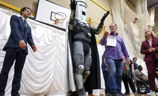 Count Binface, center, stands among other candidates during the result announcement after the Clacton by-election count at the Leisure Centre in Clacton on Sea, England, Friday, Aug. 14, 2026.(AP Photo/Richard Pelham)