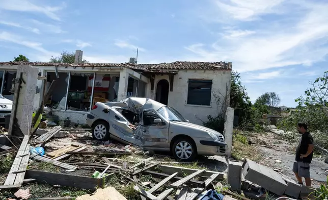 A resident stands outside a damaged home after a tornado ravaged the small village of Pomas in southern France, Tuesday Aug. 25, 2026. (AP Photo/Frederic Lancelot)