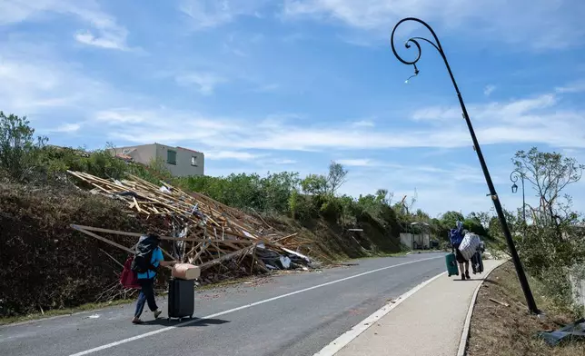 People leave with luggage after a tornado ravaged the small village of Pomas in southern France, leaving dozens injured, Tuesday Aug. 25, 2026. (AP Photo/Frederic Lancelot)