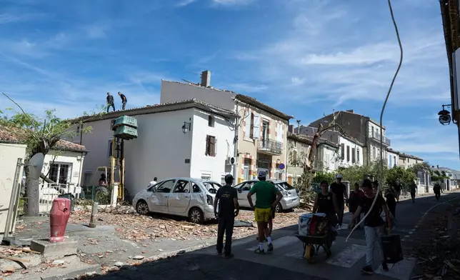 Resident watch damaged houses after a tornado ravaged the small village of Pomas in southern France, leaving dozens injured, Tuesday Aug. 25, 2026. (AP Photo/Frederic Lancelot)