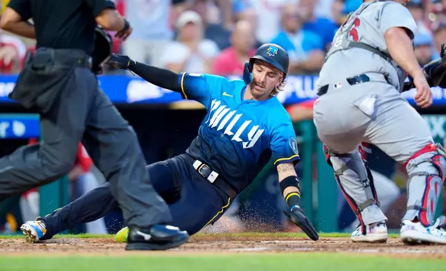 Philadelphia Phillies' Bryson Stott, center, slides into home on the double by Brandon Marsh during the second inning of a baseball game against the St. Louis Cardinals, Friday, Aug. 21, 2026, in Philadelphia. (AP Photo/Chris Szagola)