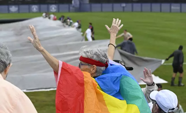 A fan reacts while the tarps are removed from the field before the inaugural Women's Professional Baseball League game between the Los Angeles Queens and the New York Heights, Saturday, Aug. 1, 2026, in Springfield, Ill. (AP Photo/Lexie Knight)