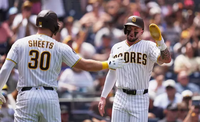 San Diego Padres' Jackson Merrill, right, celebrates with teammate Gavin Sheets after scoring from second base off an RBI single by Luis Rengifo during the second inning of a baseball game against the Pittsburgh Pirates Wednesday, Aug. 26, 2026, in San Diego. (AP Photo/Gregory Bull)
