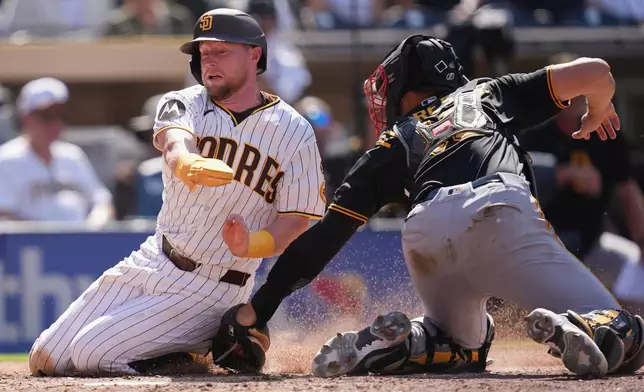San Diego Padres' Jake Cronenworth, left, is tagged out by Pittsburgh Pirates catcher Rafael Flores Jr., trying to score from second base off a single by Manny Machado during the eighth inning of a baseball game Wednesday, Aug. 26, 2026, in San Diego. (AP Photo/Gregory Bull)