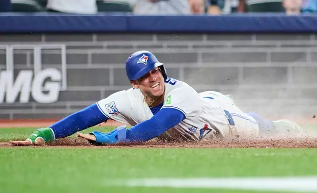 Toronto Blue Jays' George Springer slides in to score on an RBI single by Andres Gimenez during the sixth inning of a baseball game against the Boston Red Sox in Toronto, Monday, Aug. 10, 2026. (Sammy Kogan/The Canadian Press via AP)