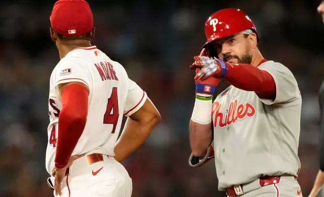 Philadelphia Phillies' Kyle Schwarber, right, gestures after hitting an RBI double as Los Angeles Angels second baseman Christian Moore stands by during the 10th inning of a baseball game Saturday, Aug. 29, 2026, in Anaheim, Calif. (AP Photo/Mark J. Terrill)