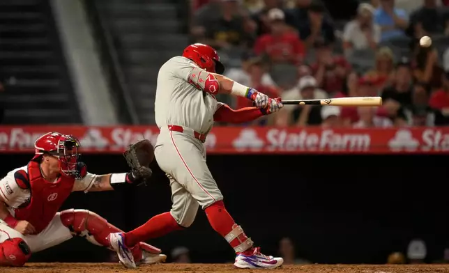 Philadelphia Phillies' Kyle Schwarber, right, hits an RBI double as Los Angeles Angels catcher Tyler Heineman watches during the 10th inning of a baseball game Saturday, Aug. 29, 2026, in Anaheim, Calif. (AP Photo/Mark J. Terrill)