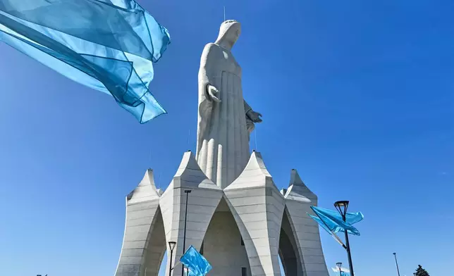 Flags wave in the wind in front of an enormous statue of the Virgin Mary that is believed to be Europe's tallest during the inauguration in the village Konotopie, Poland, Saturday, Aug. 15, 2026. (AP Photo/Claudia Ciobanu)