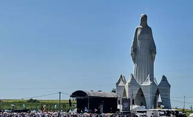 People gather near an enormous statue of the Virgin Mary that is believed to be Europe's tallest during the inauguration in the village Konotopie, Poland, Saturday, Aug. 15, 2026. (AP Photo/Claudia Ciobanu)