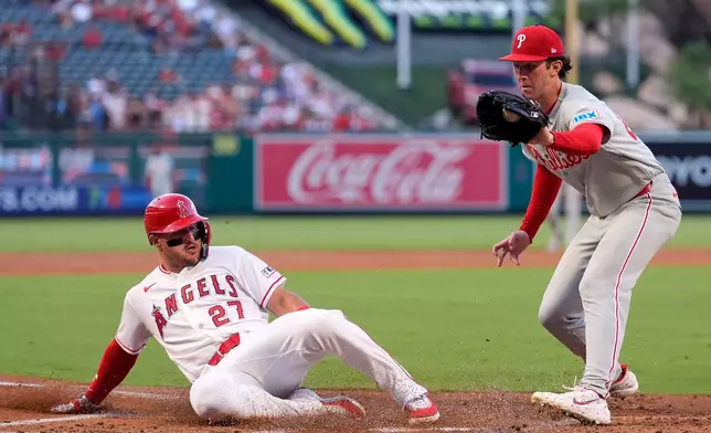 Los Angeles Angels' Mike Trout, left, scores on wild pitch by Philadelphia Phillies starting pitcher Andrew Painter, left, as Painter takes a late throw during the first inning of a baseball game Friday, Aug. 28, 2026, in Anaheim, Calif. (AP Photo/Mark J. Terrill)