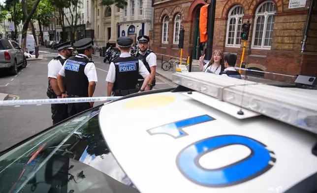 Police officers stand at the scene on Endell Street in Covent Garden, after four men were stabbed, in central London, Wednesday Aug. 5, 2026. PA Photo. (James Manning/PA via AP)
