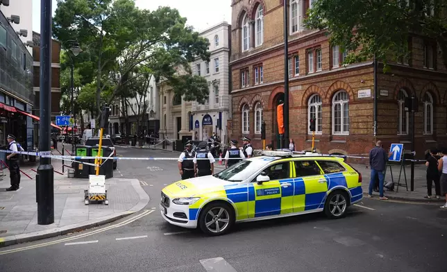 Police officers stand at the scene on Endell Street in Covent Garden, after four men were stabbed, in central London, Wednesday Aug. 5, 2026. PA Photo. (James Manning/PA via AP)