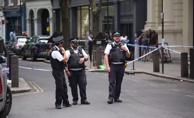 Police officers stand at the scene on Endell Street in Covent Garden, after four men were stabbed, in central London, Wednesday Aug. 5, 2026. PA Photo. (James Manning/PA via AP)