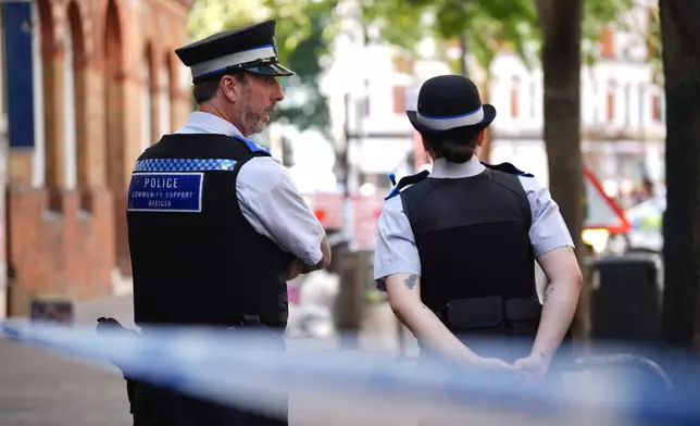 Police officers stand near the scene on Endell Street in Covent Garden, after four men were stabbed, in central London, Wednesday Aug. 5, 2026. PA Photo. (James Manning/PA via AP)