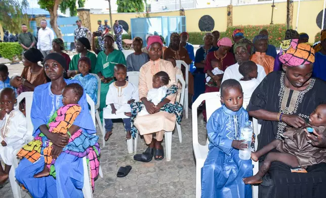 Women and children sit in the courtyard of a hotel where they are staying while waiting for the state governor to address them in Ilorin, Nigeria, Friday, Aug. 7, 2026, after being rescued from a forest where they were held following their abduction from the Woro community by gunmen in February. (AP Photo/Abubakar Khadijat)