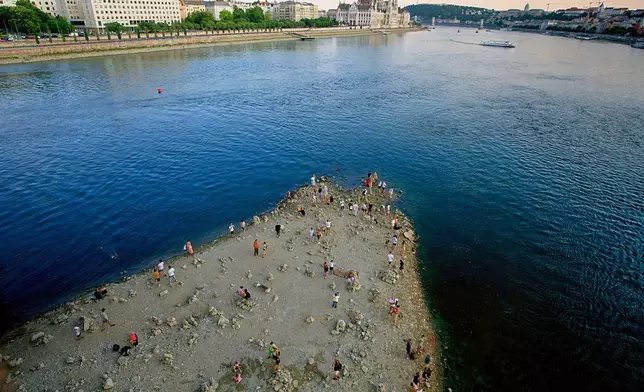 FILE - People walk on a sandbar underneath the Danube's Margareth Bridge in downtown Budapest, Hungary, on Aug. 5, 2026, as the river, which runs through 10 European countries, has receded never-before-seen low water levels. (AP Photo/Bela Szandelszky, File)