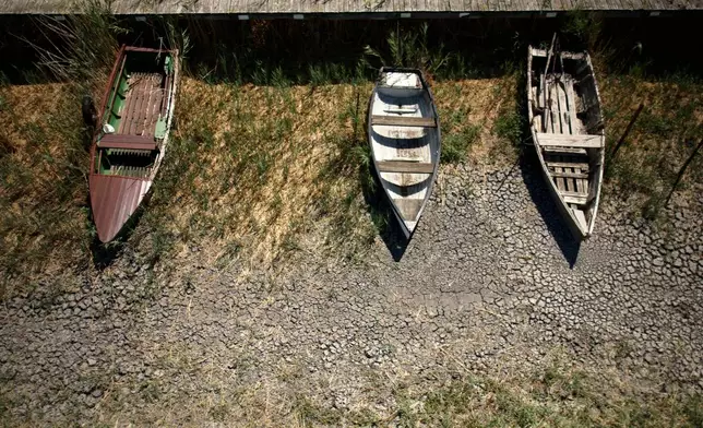Boats lie on cracked soil at a dried-out marina on Lake Velence, Hungary, on Aug. 13. 2026. (AP Photo/Bela Szandelszky)