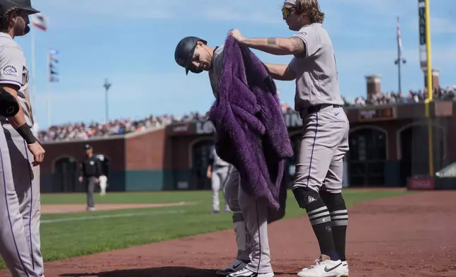Colorado Rockies' Zac Veen, right, puts a coat on Brett Sullivan after Sullivan hit a three-run home run during the seventh inning of a baseball game against the San Francisco Giants, Sunday, Aug. 16, 2026, in San Francisco. (AP Photo/Jeff Chiu)