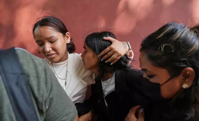 A relative consoles Jenisha, center, as she cries while waiting for the news of her father missing after flash flooding in Nepal's Nuwakot district, Friday, Aug. 28, 2026. (AP Photo/Rajesh Kumar Singh)