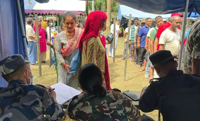 People rescued from an area cut off by flash flooding line up to register at an army camp in Nepal's Nuwakot district, Friday, Aug. 28, 2026. (AP Photo/Rajesh Kumar Singh)