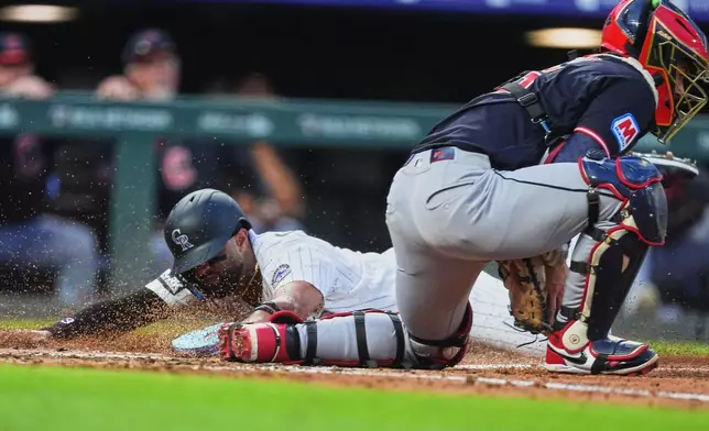 Colorado Rockies' Willi Castro, left, scores on a double hit by Troy Johnston as Cleveland Guardians catcher Patrick Bailey, right, fields the throw in the fourth inning of a baseball game Saturday, Aug. 22, 2026, in Denver. (AP Photo/David Zalubowski)
