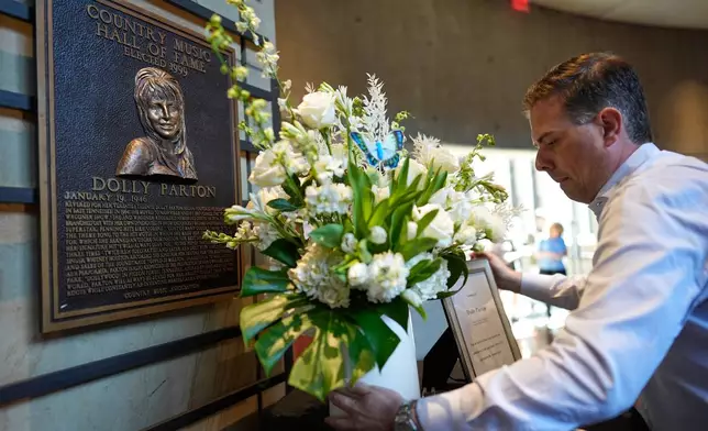 Ben Hall places flowers near Dolly Parton's plaque at the Country Music Hall of Fame on Tuesday, Aug. 25, 2026, in Nashville. (AP Photo/George Walker IV)