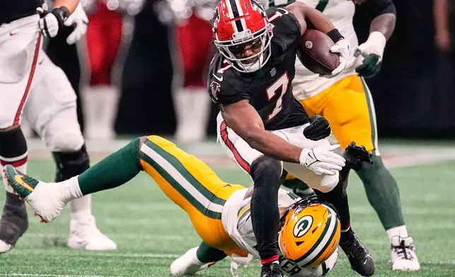 FILE - Atlanta Falcons running back Bijan Robinson, top front, runs over Green Bay Packers linebacker Quay Walker, bottom, during the first half of an NFL football game Sept. 17, 2023, in Atlanta. (AP Photo/John Bazemore, File)
