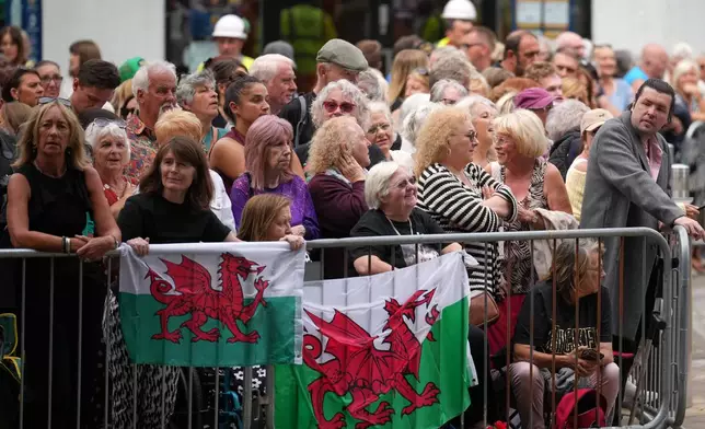 People wait behind barriers for the start of the funeral of Bonnie Tyler at St. Mary's Church in Swansea, Wales, Monday, Aug. 17, 2026. (AP Photo/Alastair Grant)