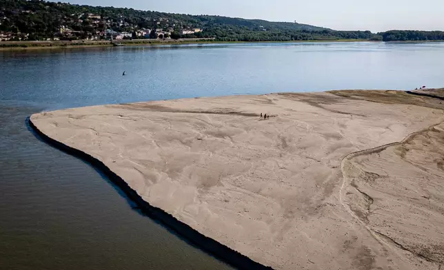 People walk on a bank of sand on the Danube River as usually submerged areas are exposed due to extreme low levels of the water following an extended period of drought in Oltenita, Romania, Saturday, Aug.1, 2026. (AP Photo/ Vadim Ghirda)