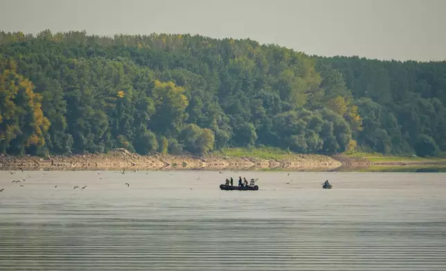 Romanian Navy EOD specialists survey the area before a controlled demolition of submerged rocks to improve water flow to the Cernavoda Nuclear Power Plant amid exceptionally low water levels on the Danube River, in Izvoarele, Romania, Monday, Aug. 3 2026. (AP Photo/ Vadim Ghirda)
