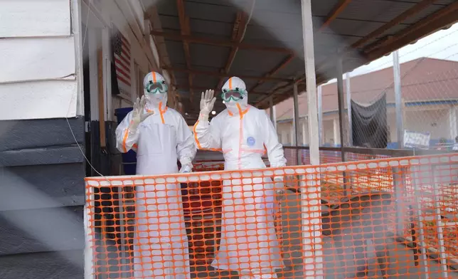 Health workers in protective gear wave inside an Ebola treatment centre in Bunia, Congo, Monday, Aug. 10, 2026. (AP Photo/Dieudonne Dirole)