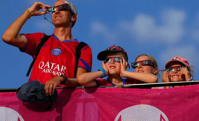 Spectators watch the solar eclipse at the European Athletics Championships in Birmingham, England, Wednesday, Aug. 12, 2026. (AP Photo/Petr David Josek)