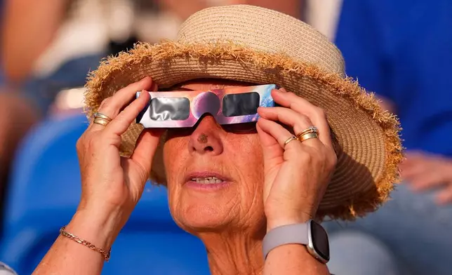 A spectators watches the solar eclipse at the European Athletics Championships in Birmingham, England, Wednesday, Aug. 12, 2026. (AP Photo/Petr David Josek)