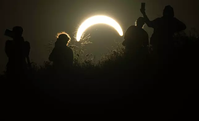 People observe a partial solar eclipse at Northala Fields in London, Wednesday, Aug. 12, 2026. (AP Photo/Frank Augstein)