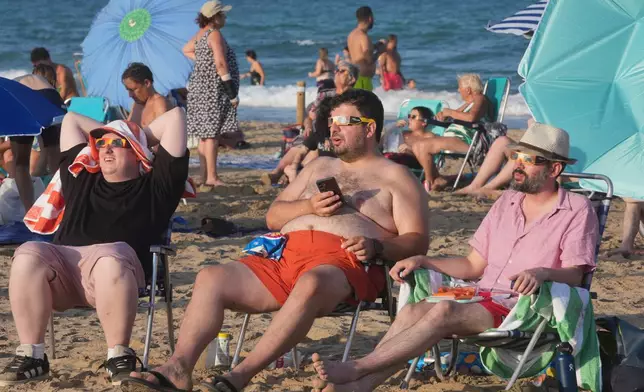 Beachgoers wearing special eclipse glasses gather before the partial phase of the solar eclipse at Puerto de Sagunto beach near Valencia, Spain, Wednesday, Aug. 12, 2026. (AP Photo/Alberto Saiz)