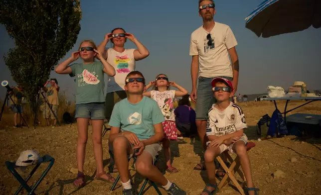 A family from Slovenia watches as the moon moves in front of the sun during a total solar eclipse in Palencia, Spain, Wednesday, Aug. 12, 2026. (AP Photo/Emilio Morenatti)